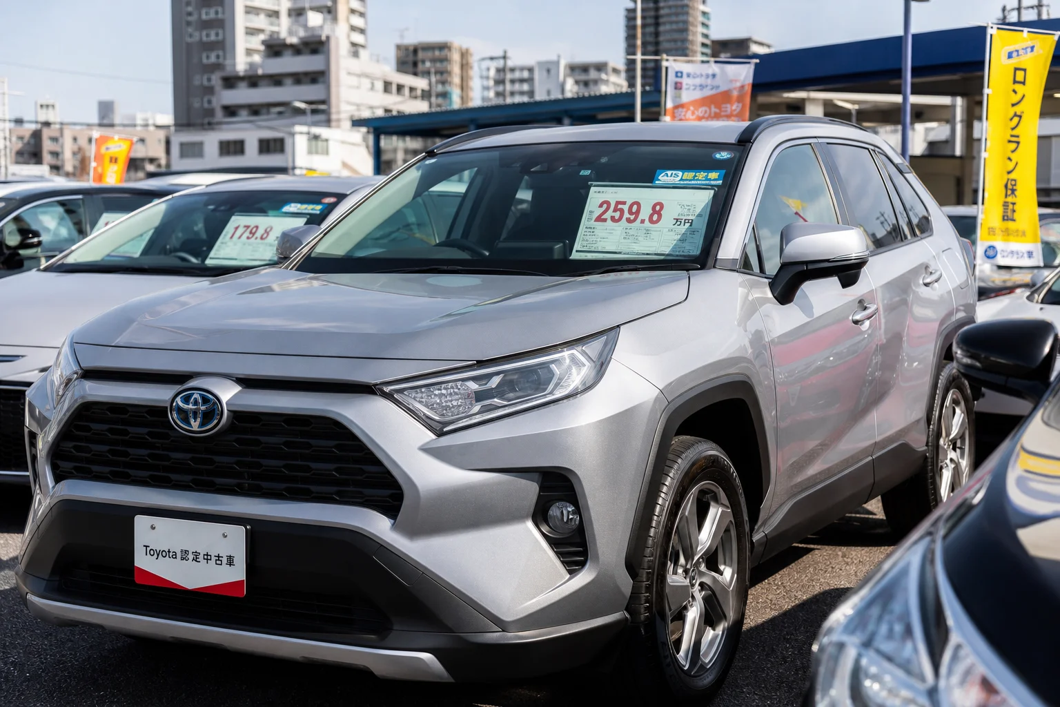 A realistic photo-style wide shot of a well-lit used car dealership lot in urban Japan, rows of clean and polished used cars parked under bright midday sunlight, with a price tag and inspection sticker visible on a windshield in the foreground, shallow depth of field drawing focus to a silver SUV, modern city buildings softly blurred in the background, warm and trustworthy atmosphere, high-resolution commercial photography style